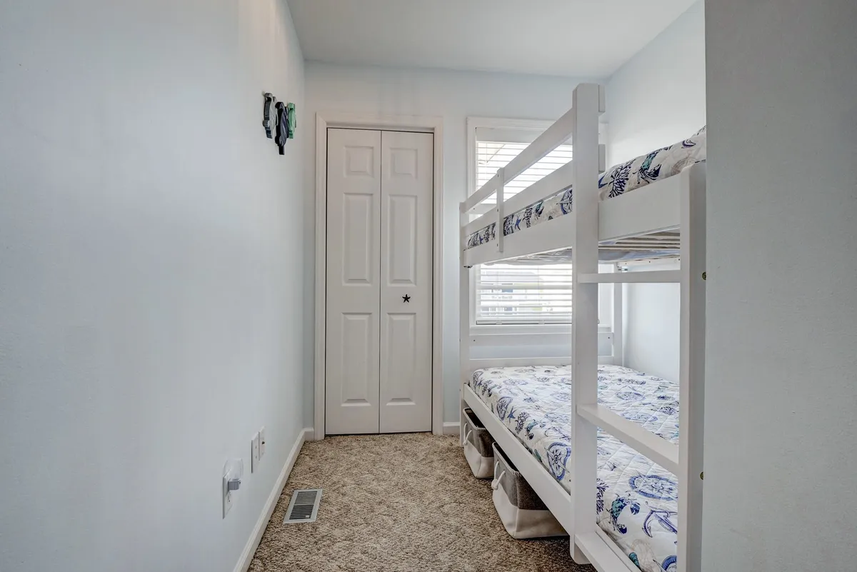 A cozy third bedroom with a twin-over-twin bunk bed set beside a window. The room has a playful, welcoming feel ideal for children, with space for games and imaginative activities.