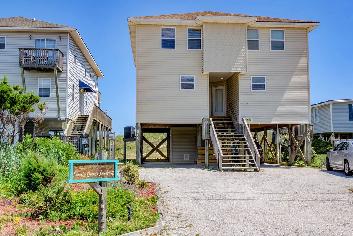 The welcoming exterior of Luna's Ocean Lookout, featuring stairs leading to the entrance, a signboard, and lush landscaping, sets the stage for a home base that's both inviting and pet-friendly.
